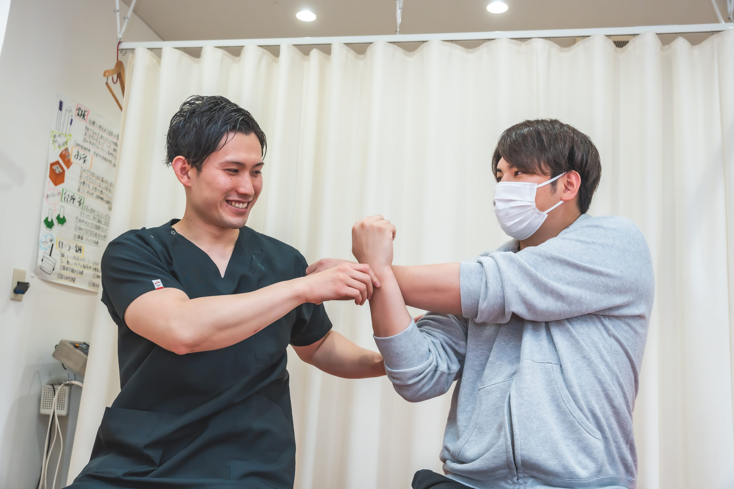 男性スタッフが患者様の手を持ちストレッチの指導をしています。